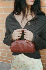 Bolso mini tipo bowling color negro charol, con doble asa de mano y correa bandolera extraíble. Tiene doble compartimento con cierre de cremallera y herrajes dorados.