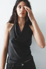 Top negro de satén con cuello halter drapeado ajustable con lazada en el cuello y espalda descubierta con lazada.