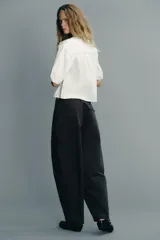 Camisa blanca de cuello bobo con bordados, escote pico con lazada, manga corta abullonada con elástico y cierre frontal con botones.