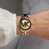 Reloj Michael Kors modelo Hally para mujer, con caja y pulsera de acero inoxidable color dorado. El dial presenta el logo MK en relieve. Resistente al agua hasta 50 metros.