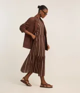Vestido midi evasé sin mangas, confeccionado en viscosa, con cuello alto, corte en la cintura, recortes fruncidos en la pollera y rayas verticales desencontradas.
