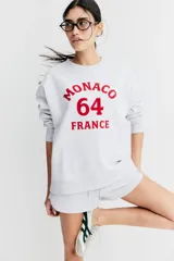 Buzo gris melange oversized con cuello redondo ribeteado acanalado y diseño de texto en rojo con la leyenda "Monaco 64 France". Modelo con hombros caídos y remate acanalado en puños y bajo. Interior cepillado suave.