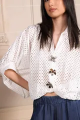 Camisa blanca calada con botones y mangas cortas. Incluye tres prendedores con forma de flor.