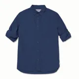 Camisa de popelina verde con cuello abotonado, cierre frontal con botones, bolsillo de parche en el pecho izquierdo, mangas largas con trabillas para enrollar y dobladillo camisero.