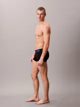 Pack de tres bóxers trunk Calvin Klein de microfibra negra con cintura elástica con el logo de la marca en azul, gris y blanco.