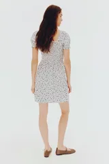 Vestido corto de popelina de algodón con estampado floral azul. Presenta escote cuadrado con elástico, mangas cortas abullonadas con fruncido elástico, cuerpo ajustado fruncido y falda con vuelo.