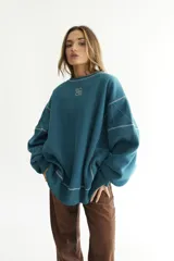 Buzo negro de felpa de algodón con pespuntes en zigzag color celeste y logo bordado en el pecho.
