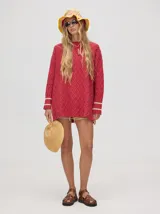 Sweater color crema con tejido en ochos, cuello redondo, puños acanalados con doble raya azul y tajos a los costados.
