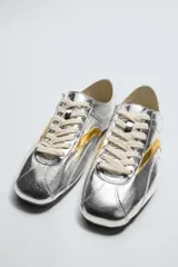 Zapatillas deportivas plateadas de cuero con efecto metalizado, cordones y suela plana. Diseño de punta redonda y colaboración especial Harry Lambert for Zara x Disney.