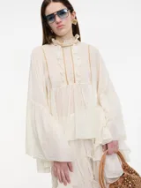 Blusa negra de mangas largas amplias con botón en el cuello trasero.
