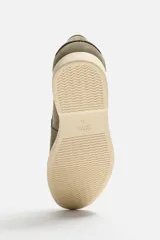 Mocasín casual de hombre color verde oliva, fabricado en cuero con acabado serraje, corte liso con detalle de bordón, horma redonda y suela a contraste color crema.