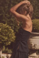 Top negro strapless de tejido fluido con frunces ajustables con cordones en los laterales y aberturas laterales en el ruedo.