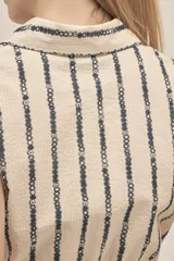 Vestido camisero color crema con rayas verticales negras y estampado floral, confeccionado en tejido seersucker de algodón con botones nacarados y lazo para ajustar la cintura.