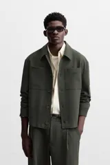Sobrecamisa verde oscuro de corte cuadrado, con cuello solapa, manga larga con puños abotonados, bolsillos de parche en el pecho y bolsillos laterales en la cadera. Cierre frontal con botones.