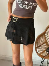 Minifalda negra de encaje con forro interior y cinturón con hebilla dorada.