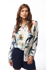 Camisa de manga larga con estampado floral en tonos azules, verdes, naranjas y amarillos sobre fondo blanco.