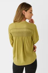 Camisa color crema de algodón con cuello a la base, corte holgado, cierre frontal con botones y mangas largas con puños abotonados.