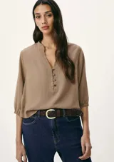 Blusa marrón con cuello mao, escote en V y mangas 3/4 con puños elásticos.