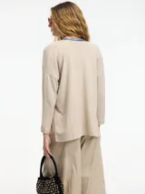Cardigan negro de tejido con botones en la parte delantera y tajos verticales laterales.