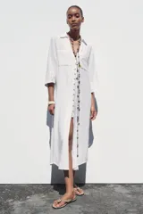 Vestido camisero largo color verde claro, confeccionado en lino. Tiene cuello solapa, escote en V, manga tres cuartos con trabilla y botón, bolsillos delanteros de plastrón, aberturas laterales en el ruedo y cierre frontal con botones.