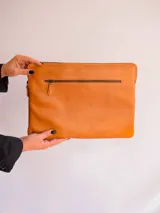 Funda porta laptop de cuero negro con cierre superior y bolsillo externo con cierre.
