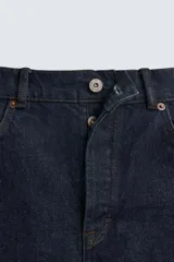Jeans de corte slim fit confeccionados en denim de algodón sin lavados, color azul oscuro. Cierre frontal con botones y cinco bolsillos.