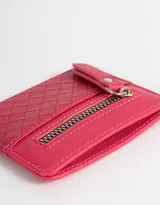 Tarjetero color fucsia de cuerina con diseño trenzado en la parte inferior y cierre superior con tirador.