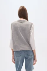 Chaleco de punto sin mangas confeccionado en rayón con efecto confetti en color gris melange. Presenta un diseño frontal en jacquard con diversos motivos como una herradura, una luna, un pájaro y estrellas, con cuello redondo y terminaciones acanaladas.