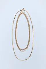 Set de tres collares dorados de diferentes largos. Incluye dos collares de cadena de eslabones metálicos y un collar de cadena tipo malla metálica.