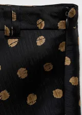 Falda midi negra con estampado de lunares color dorado.