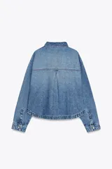 Cazadora de denim celeste de corte recto, con cuello solapa, manga larga, bolsillos delanteros de plastrón y cierre frontal con botones metálicos.