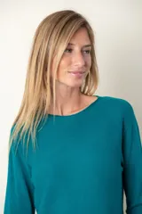 Buzo fino color verde, con detalle de bolsillo y botón de strass en el frente.
