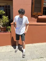 Remera blanca de algodón con cuello redondo y manga corta. Estampado frontal con diseño de paisaje playero enmarcado.