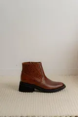 Bota corta color marrón con textura símil cuero de cocodrilo, caña baja, punta redondeada y taco cuadrado.