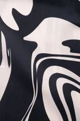 Camisa de manga corta con cuello tipo camp, con estampado abstracto en tonos beige y negro.