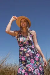 Vestido largo negro con estampado floral multicolor, escote en V, breteles finos y volados en el cuello.