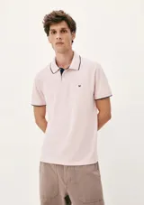 Camisa polo color rosa claro con cuello clásico, tapeta de dos botones y bordado de logo en el pecho. Presenta ribete azul marino en cuello y mangas. Corte clásico.
