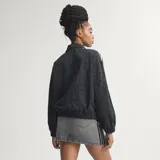 Campera deportiva Adidas Originals modelo Firebird, color negro con estampado animal print sutil. Presenta cuello camisero, cierre frontal y las icónicas tres tiras blancas en las mangas. Lleva el logo del trébol bordado en blanco en el pecho.