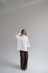 Sweater blanco de corte recto con cuello alto y aberturas laterales.