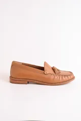 Mocasines de cuero color marrón claro con detalle de borlas en el empeine y costuras decorativas.