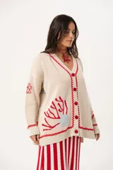 Saco oversize tejido con ilustraciones inspiradas en corales, peces, estrellas de mar y tortugas. Presenta galón picot en rojo en cartera y puños, y botones a tono.