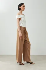 Pantalón de lino color marrón claro, de corte recto y tiro alto, con cintura elástica ajustable con cordón.