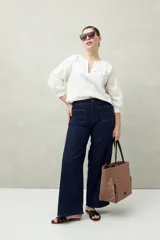 Pantalón de jean azul oscuro, de corte ancho y tiro alto, con bolsillos delanteros cuadrados y amplios.