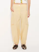 Pantalón cargo color amarillo claro, confeccionado en poplin asargado. Tiene cuatro bolsillos plaqué con refuerzos triangulares en hilo crudo. El ruedo lleva jareta para ajustar y abuchonar con lazo.