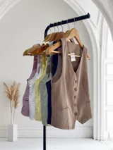 Chaleco sastrero corto con escote en V y cierre frontal con botones.