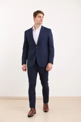 Traje de vestir azul marino, compuesto por saco de dos botones y pantalón de corte slim. Incluye camisa blanca de vestir y zapatos marrones acordonados.