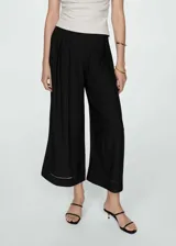 Pantalón negro de corte ancho con tablas, tejido fluido y largo hasta el tobillo.