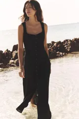 Vestido midi negro de lino con escote cuadrado, sin mangas, con botones dorados en el frente y abertura en el ruedo.