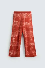 Pantalón relaxed fit de punto ligero tejido en hilatura de algodón color ladrillo con estampado a cuadros difuminados en blanco. Cintura elástica ajustable con cordón y bolsillos laterales.