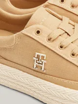 Zapatillas Tommy Hilfiger color beige de lino orgánico con monograma TH dorado en el lateral.